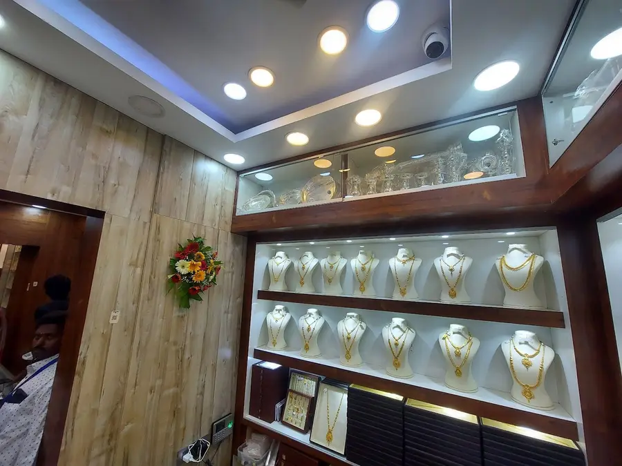 Inside the shop: warm wood, ceiling spotlights and lit glass cases of necklaces on white display busts.